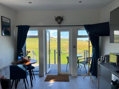 uma cozinha com uma porta que abre para um pátio com uma mesa e cadeiras em Island Coorie em Kilmaluag