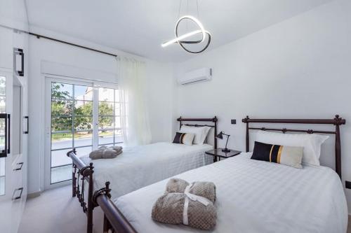 2 bedden in een slaapkamer met witte muren en een raam bij Katris Luxury Homes #1 in Triánta