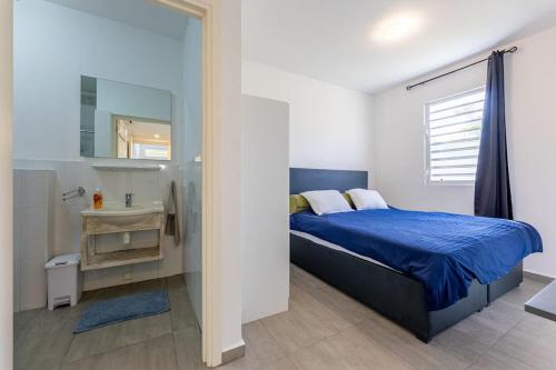 a bedroom with a blue bed and a sink at Cocobana Resort two-bedroom apartment ground floor in Willemstad