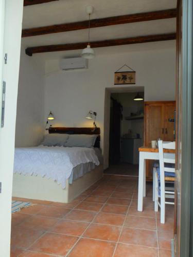 a bedroom with a bed and a table and a table and chairs at Kavousi Cottages - H Petra in Kavoúsion