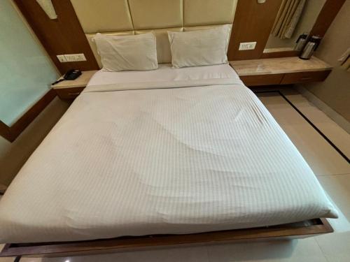 un grande letto bianco in una piccola stanza di Hotel Vinnie a Jaipur