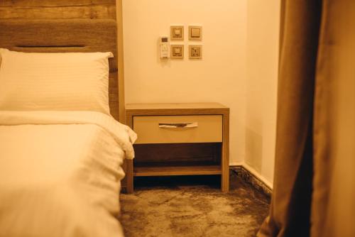 pokój z łóżkiem i stolikiem nocnym z łóżkiem o wymiarach sześciu w obiekcie Hols Apartments w Kadunie