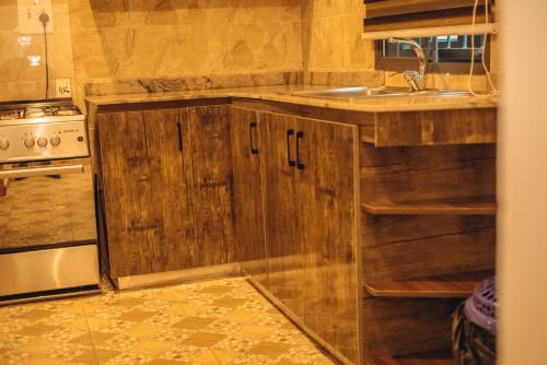 una cocina con armarios de madera y fregadero en Hols Apartments, en Kaduna