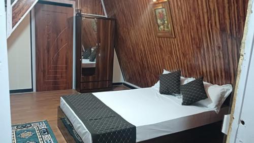 a bedroom with a bed and a wooden wall at Orchard Farmstay in Bijanbāri Bāzār
