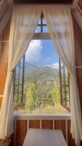 a window with a view of a mountain view at Orchard Farmstay in Bijanbāri Bāzār