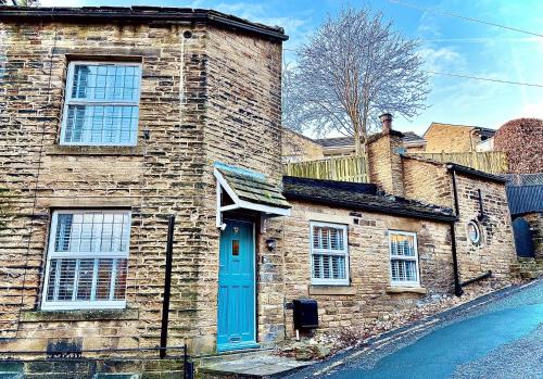 een bakstenen gebouw met een blauwe deur op een straat bij Nine Cooper Lane, Holmfirth in Holmfirth