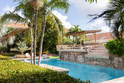 a swimming pool in a resort with palm trees at Cocobana Resort two-bedroom apartment ground floor in Willemstad