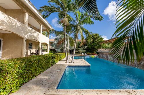 a swimming pool in the backyard of a house with palm trees at Cocobana Resort two-bedroom apartment ground floor in Willemstad