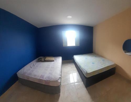 Duas camas num quarto com uma parede azul em Chácara Recanto da Paz em Igaratá