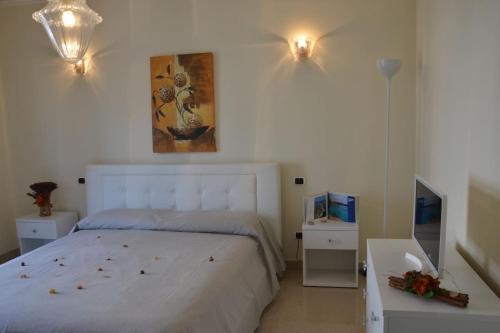 een slaapkamer met een wit bed en een televisie bij Appartamento centrale elegante in Olbia