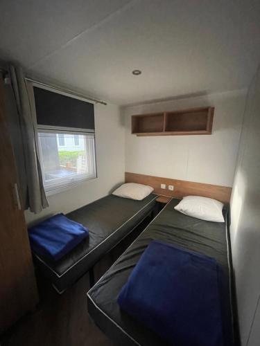 une petite chambre avec deux lits et une fenêtre dans l'établissement Mobil-Home Bougainvilliers 1, à Valras-Plage
