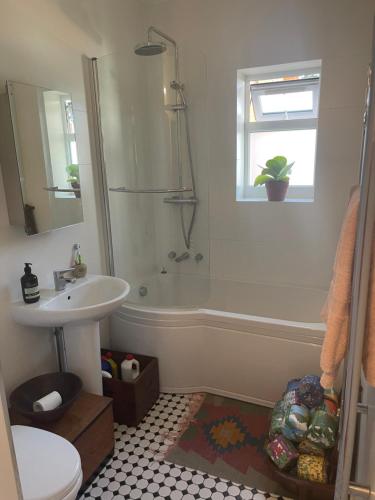 La salle de bains est pourvue d'un lavabo, d'une douche et d'une baignoire. dans l'établissement 4 Birkbeck Road Beckenham BR3 4SN, à Elmers End