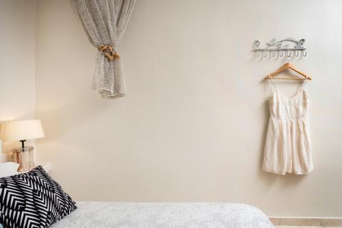 a white bedroom with a dress hanging on a wall at Aggeliki's Diamond in Agia Anna Naxos