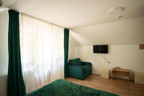 una sala de estar con una silla verde y una ventana en GREEN ROSIA, en Lazuri