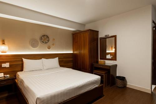 Dormitorio pequeño con cama y espejo en Lantern Hotel en Ho Chi Minh