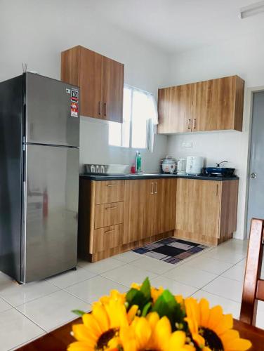 a kitchen with a stainless steel refrigerator and wooden cabinets at Santai at KotaWarisan KLIA Netflix in Sepang