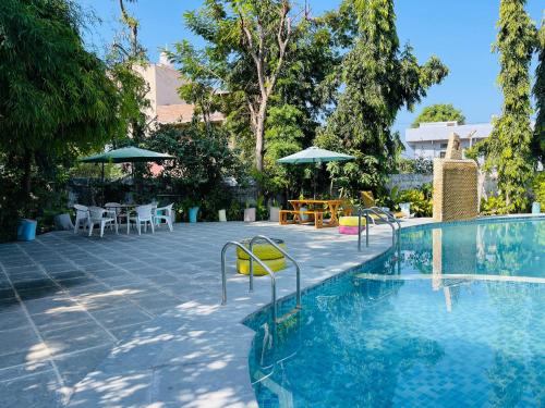 una piscina con sillas, mesas y sombrillas en Dev Villa Resort en Rājsamand