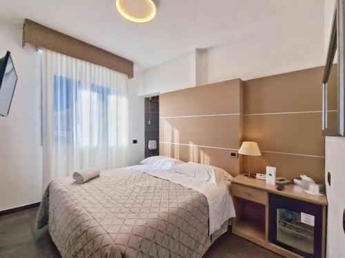 Schlafzimmer mit einem Bett, einem Schreibtisch und einem Fenster in der Unterkunft Hotel Tiffany in Marina di Massa