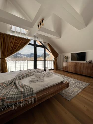 a bedroom with a large bed and a large window at Elviu Guesthouse in Lacu Rosu