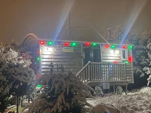 a house with christmas lights on it in the snow at The Little John Petite Cosy Log Cabin - Sleeps 2, great for romantic breaks, couples, single guests, near Sherwood Forest at Fairview Farm, Nottingham set in 88 acres in Blidworth
