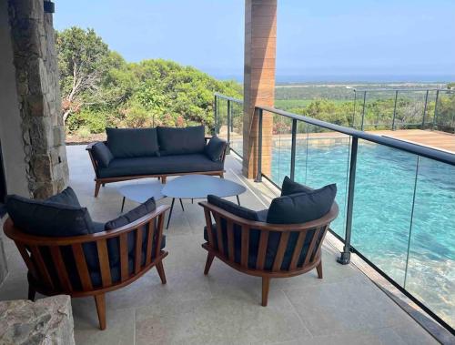 d'une terrasse avec un canapé et des chaises sur un balcon. dans l'établissement Bergerie vue mer avec piscine, à Ventiseri