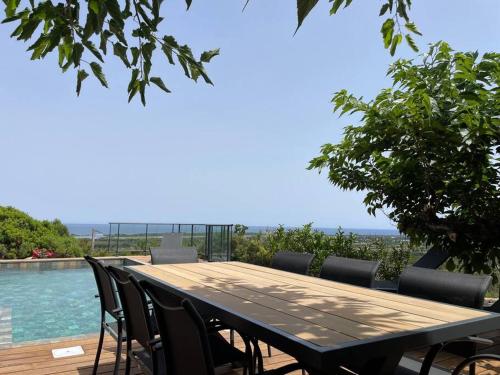 - une table et des chaises en bois à côté de la piscine dans l'établissement Bergerie vue mer avec piscine, à Ventiseri