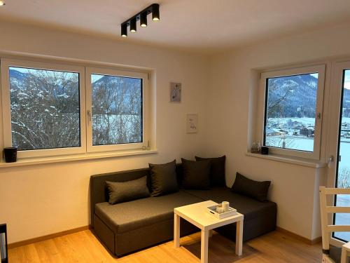 a living room with a couch and three windows at Haus Sonnenwinkl in Kössen