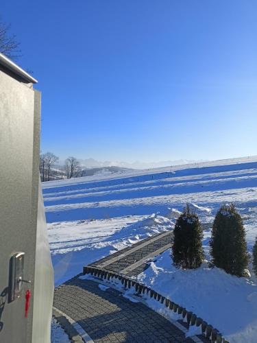 einen schneebedeckten Hof mit zwei Bäumen und einem Gebäude in der Unterkunft Luxury Glamp in Bańska Niżna