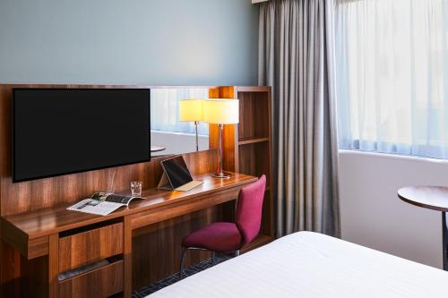 a hotel room with a desk with a tv and a chair at Mercure Telford Centre Hotel in Telford