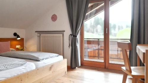 a bedroom with a bed and a large window at Goldvogel Apartments in Fischen