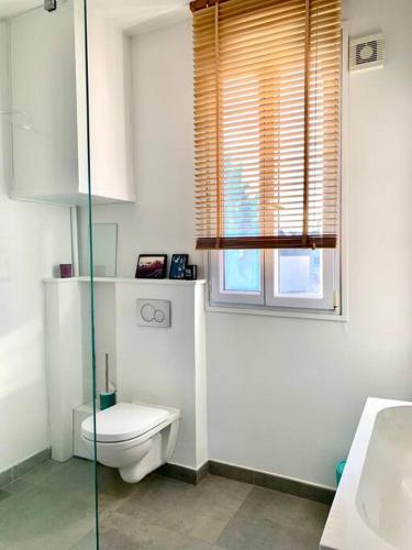 een witte badkamer met een toilet en een raam bij appartement moderne et lumineux in Clamart