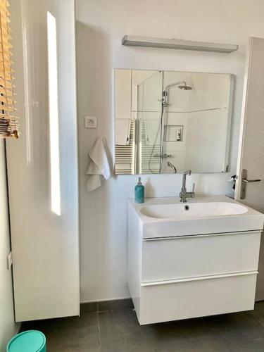 een witte badkamer met een wastafel en een spiegel bij appartement moderne et lumineux in Clamart