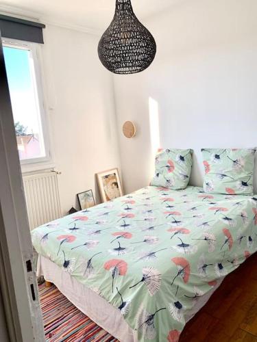 een slaapkamer met een bed met een dekbed met bloemen bij appartement moderne et lumineux in Clamart