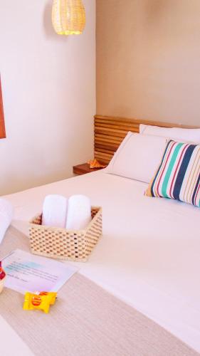 a bedroom with a bed with a basket of towels at Chalés Mahalo J - Pontal de Maceió - Fortim in Fortim