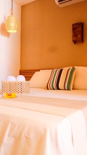 a bedroom with a bed with a white sheets and pillows at Chalés Mahalo J - Pontal de Maceió - Fortim in Fortim
