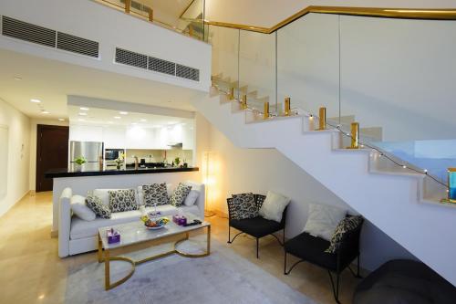 a living room with a couch and a staircase at Luxury Apartment by the Sea with Amazing Amenities at Pearl Qatar in Doha