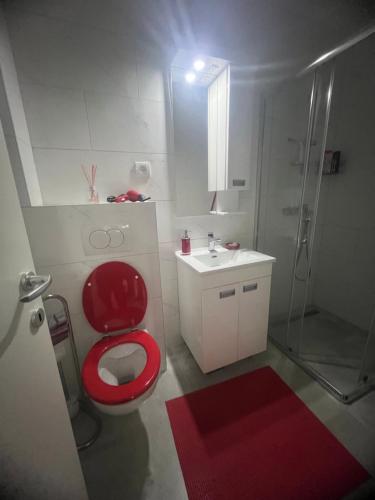 La salle de bains est pourvue d'une douche et de toilettes rouges. dans l'établissement Lux studio sa saunom Ampelitsi, à Ledine