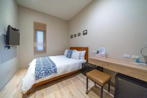 a bedroom with a bed and a desk with a television at Enjoy Homestay in Tainan