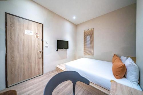 a small bedroom with a bed and a television at Enjoy Homestay in Tainan