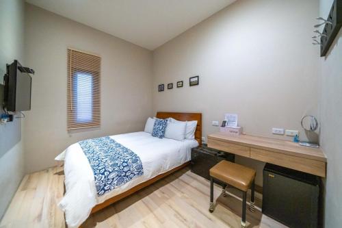 a bedroom with a bed and a desk with a television at Enjoy Homestay in Tainan