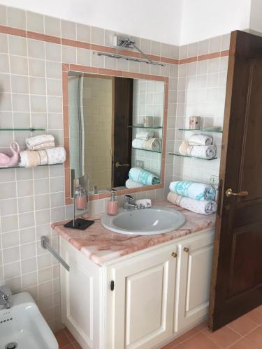y baño con lavabo, espejo y toallas. en Villa Molara, en Baja Sardinia