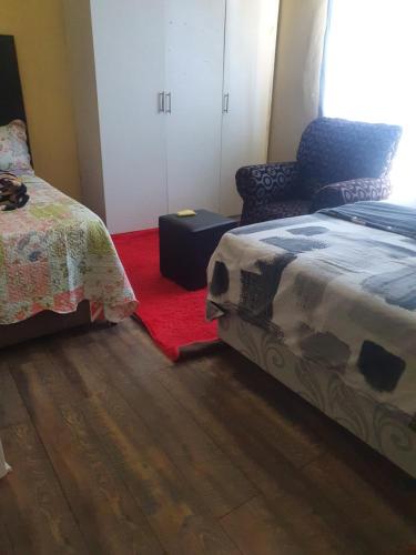 a bedroom with two beds and a red rug at Randgate guesthouse in Randfontein