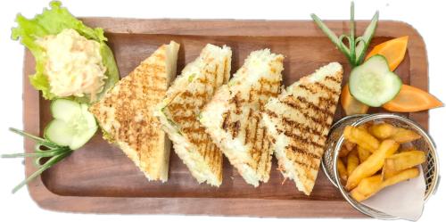 un plato de sándwiches y papas fritas en una tabla de cortar en XCELSIOR HOTEL & SPA en Shillong