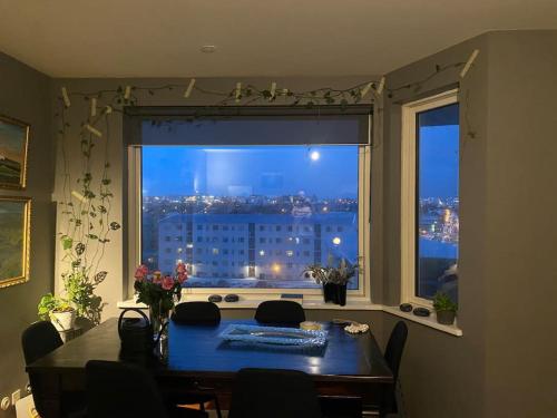 a dining room table with a view of a city from a window at Private room in a shared apartment with amazing view in Reykjavík