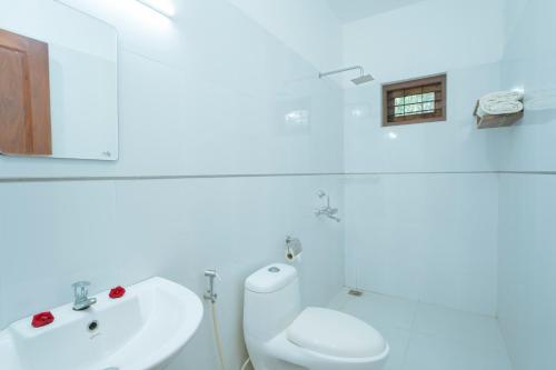 une salle de bain blanche avec un lavabo et des toilettes dans l'établissement Ananda Marari Heritage Villa, à Alappuzha