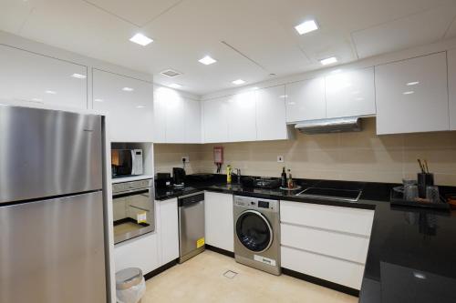a kitchen with white cabinets and a washer at Luxury Apartment by the Sea with Amazing Amenities at Pearl Qatar in Doha