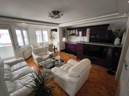 ein Wohnzimmer mit weißen Sofas und eine Küche in der Unterkunft Stan u centar in Pirot