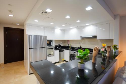 a kitchen with white cabinets and a black counter top at Luxury Apartment by the Sea with Amazing Amenities at Pearl Qatar in Doha