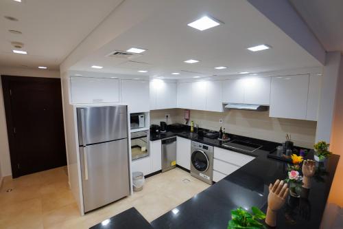 a kitchen with white cabinets and a stainless steel refrigerator at Luxury Apartment by the Sea with Amazing Amenities at Pearl Qatar in Doha