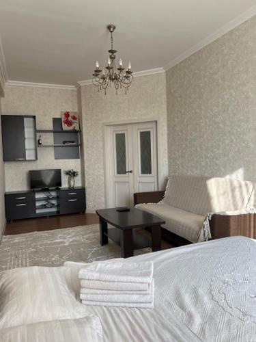 a bedroom with a bed and a living room with a couch at PROMENADE BISHKEK in Bishkek